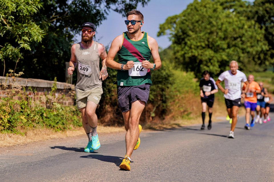 A runner racing solo along a tree-lined park road